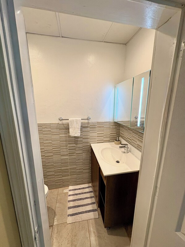 A bathroom with a white sink, a mirror, and a towel rack.