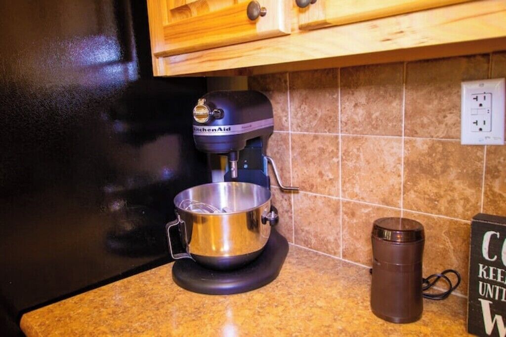 A kitchen with a KitchenAid mixer, a stainless steel mixing bowl, and a coffee maker on the counter.