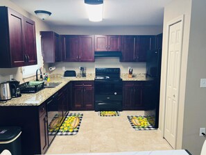A kitchen with dark wooden cabinets, a black stove, and a granite countertop.