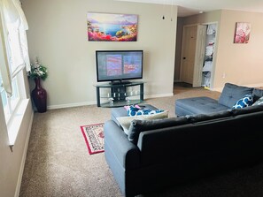 A living room with a TV, a sofa, a decorative vase, and a painting on the wall.