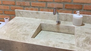 A bathroom with a marble sink, a faucet, and a soap dispenser.