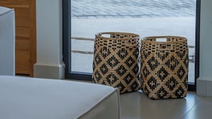 Two woven baskets placed on a tiled floor near a window with a view of a paved area outside. - Villa in Exclusive Community 3-Min Drive to Beach w/ Private Pool, Sauna & Cold Plunge (Hacienda Pinilla)