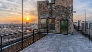 Una terrazza sul tetto con un muro in mattoni, ampie finestre e una ringhiera in metallo.