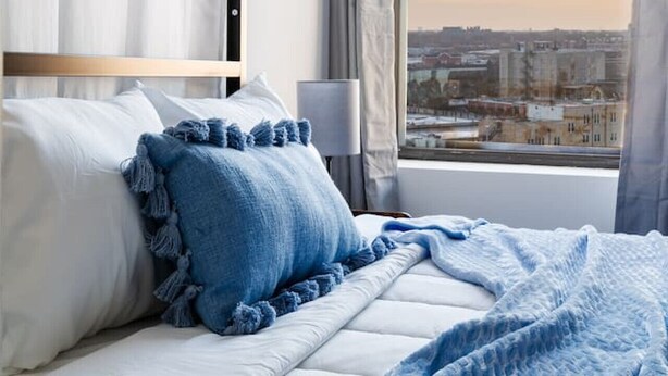 Camera d'albergo con un letto, vista sulla città e una finestra con tende.