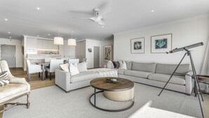 A modern living room with a sectional sofa, a round coffee table, and a telescope. - Waterfront Escape, Princes Wharf with Carpark (Auckland)