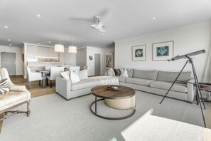 A modern living room with a sectional sofa, a round coffee table, and a telescope. - Waterfront Escape, Princes Wharf with Carpark (Auckland)
