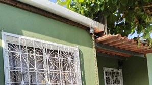 A house with a green exterior, white window frames, and a decorative white metal grille.