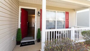 A house with a red door, a white porch, and a welcome mat.