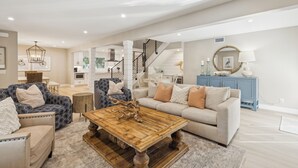 Ein geräumiges Wohnzimmer mit einem Holztisch, zwei Sofas und einer Treppe, die zu einer oberen Etage führt.