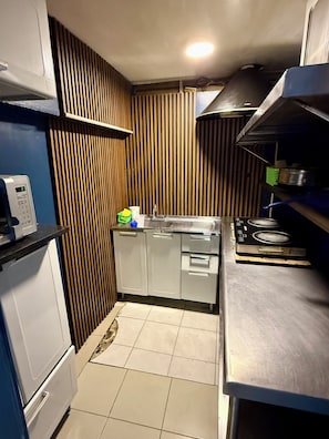 A compact kitchen with a built-in oven, a microwave, and a gas stove. - Capital Hostal (Mexico City)