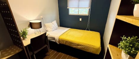 Una habitación pequeña y funcional con cama, escritorio y ventana.