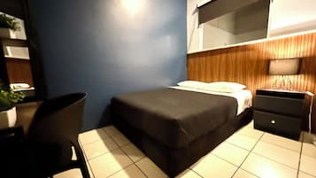 Une chambre à coucher comprenant un lit, un bureau, une chaise, une commode et une plante en pot.
