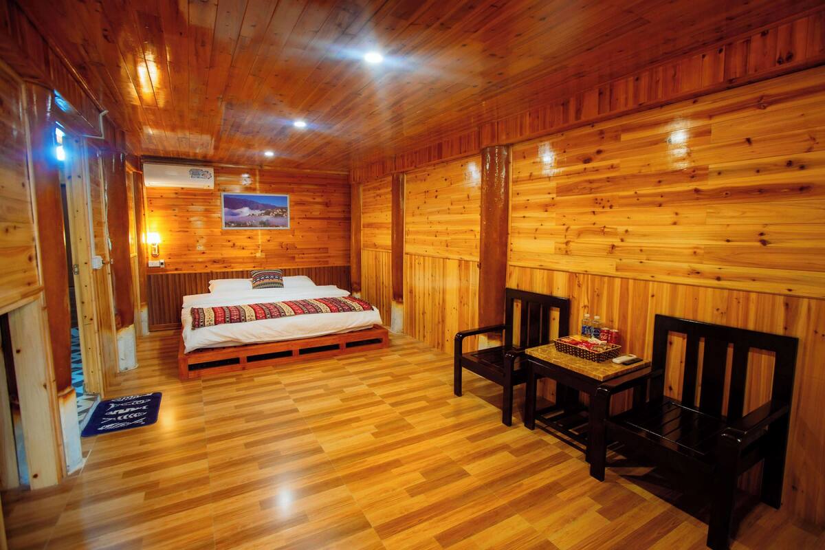 Ein Zimmer mit Holzboden, einem Bett, zwei Stühlen, einem Tisch und einem Bild an der Wand.