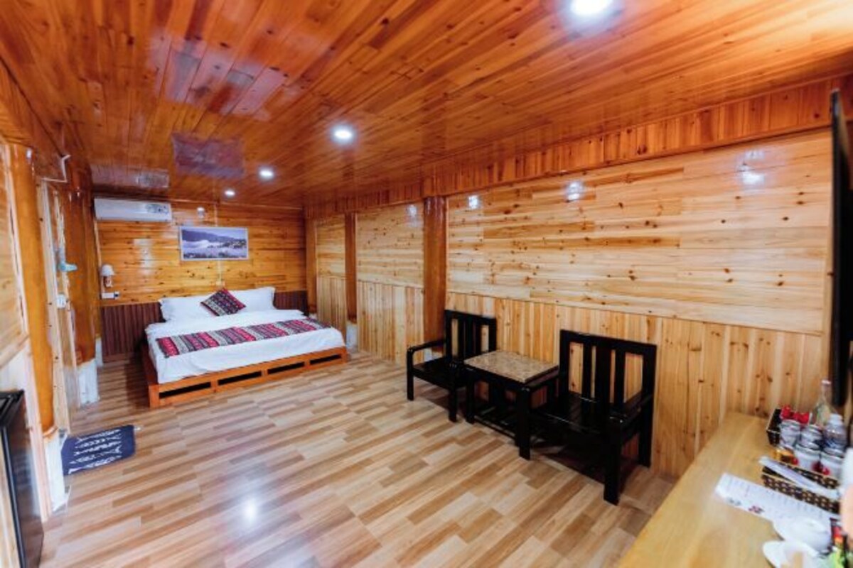 Una habitación de cabaña de madera con una cama, una mesa y sillas.