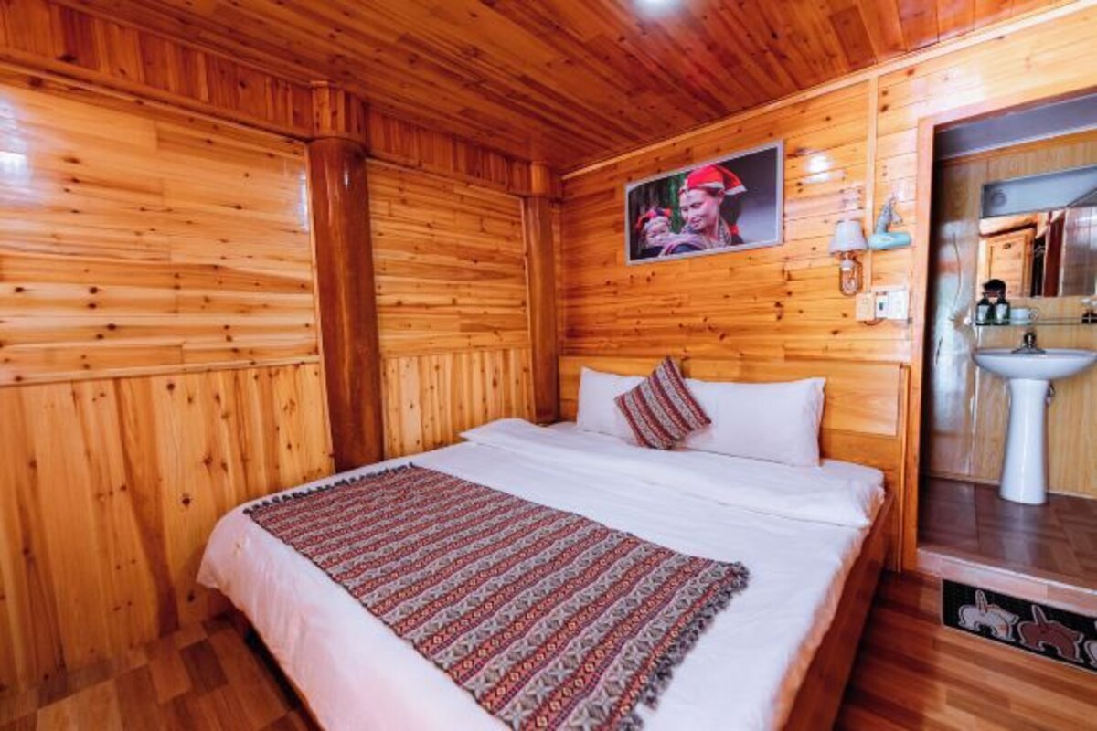 Una habitación con paneles de madera, una cama, un cuadro en la pared y un lavamanos.