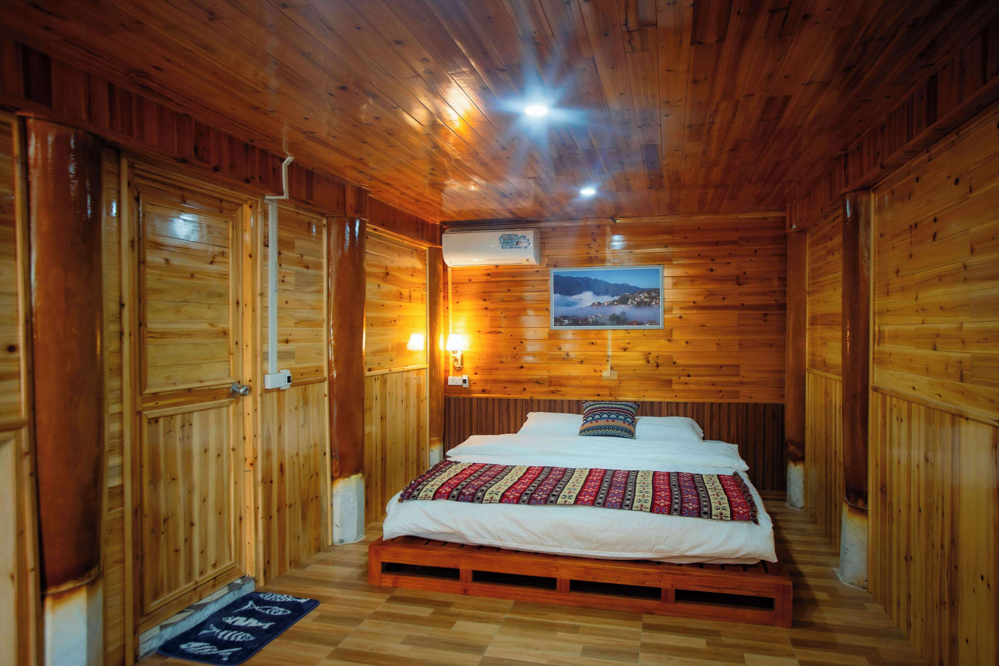 Een houten kamer met een bed, een aan de muur hangend schilderij en een airconditioning.