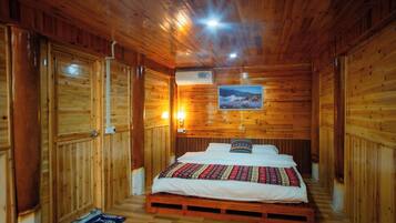 Een houten kamer met een bed, een aan de muur hangend schilderij en een airconditioning.