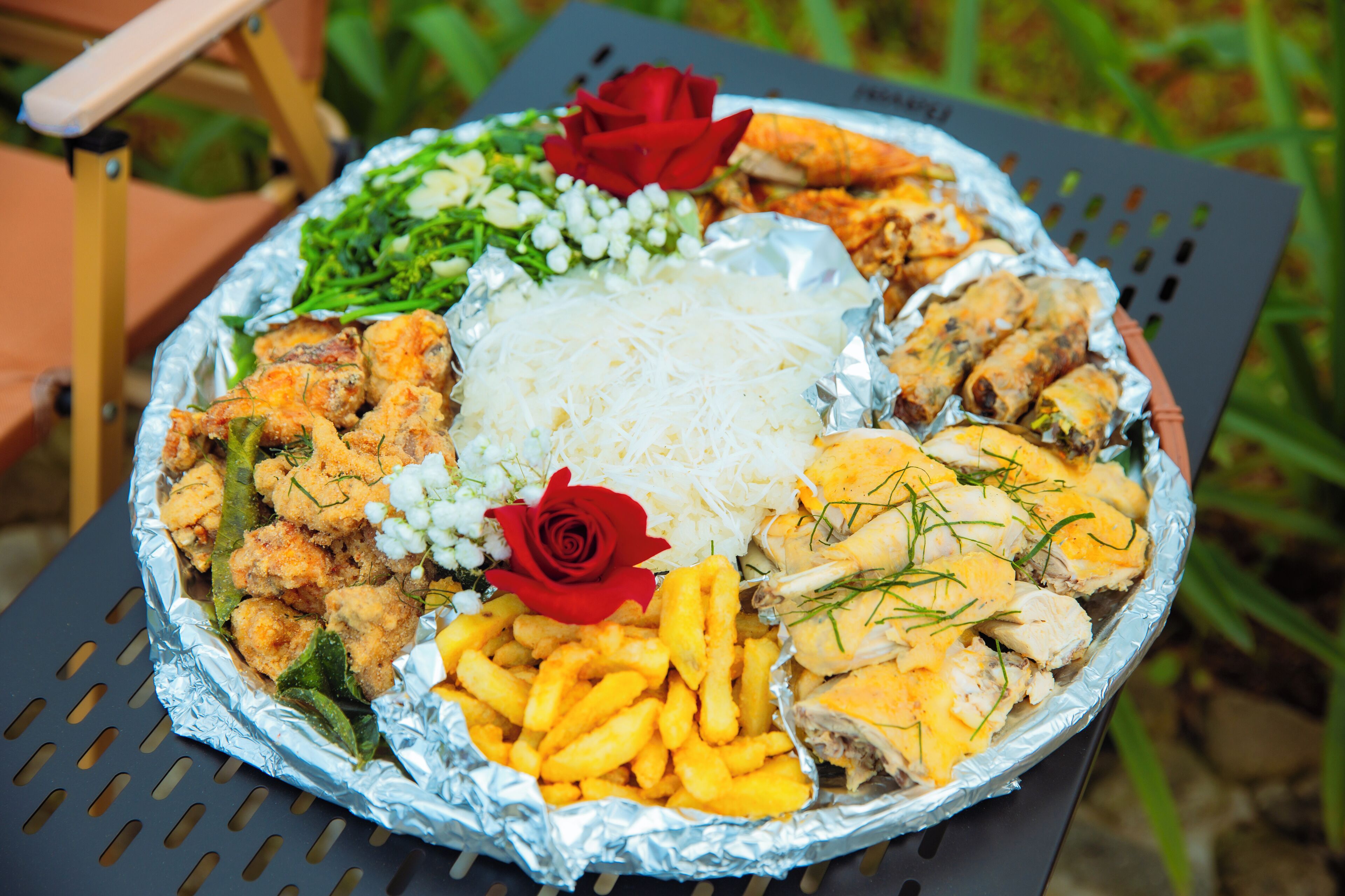 A large round table with a variety of foods including fried items, rice, and garnishes.