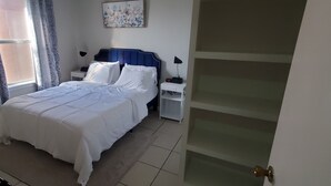 Ein ordentlich bezogenes Bett mit weißen Leinen, einem blauen Kopfteil und zwei Nachttischen mit Lampen.