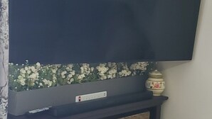 Eine dunkle Holzunterhaltungsecke mit einem flachbildfernseher darüber, einer dekorativen Vase und Korbwäschekörben.