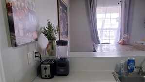 Eine Küche mit Arbeitsplatte, Spüle, Deckenventilator und einem Fenster mit Vorhängen.