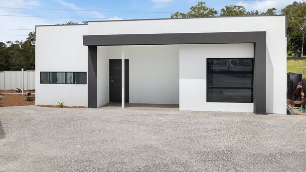 Un bâtiment moderne doté d’un toit plat, d’une grande fenêtre et d’une porte.