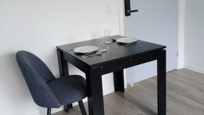 Un petit coin repas avec une table dressée pour deux personnes, une chaise et une porte dotée d’une poignée.