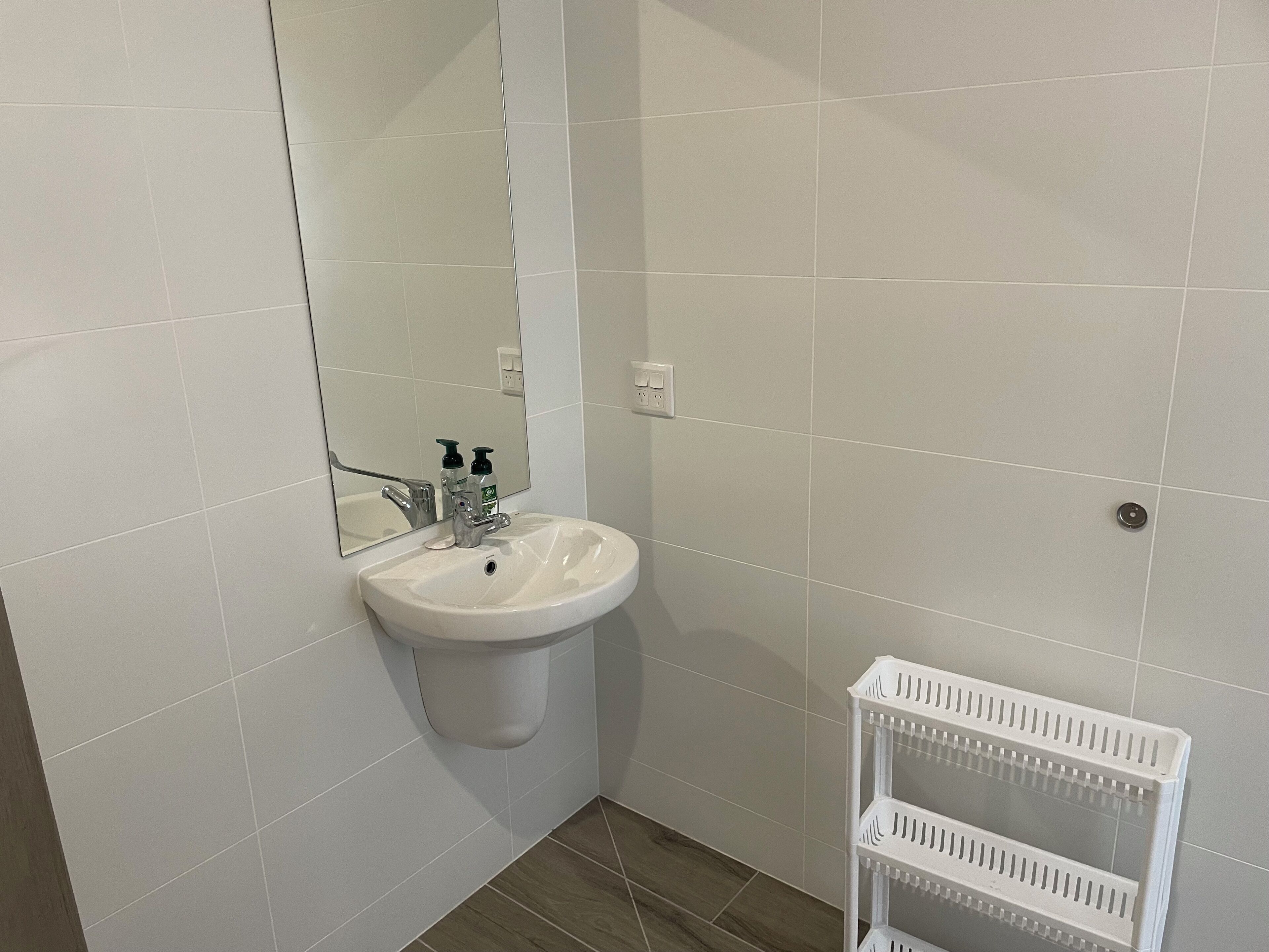 Een badkamer met een witte wastafel, spiegel en witte betegelde wanden.