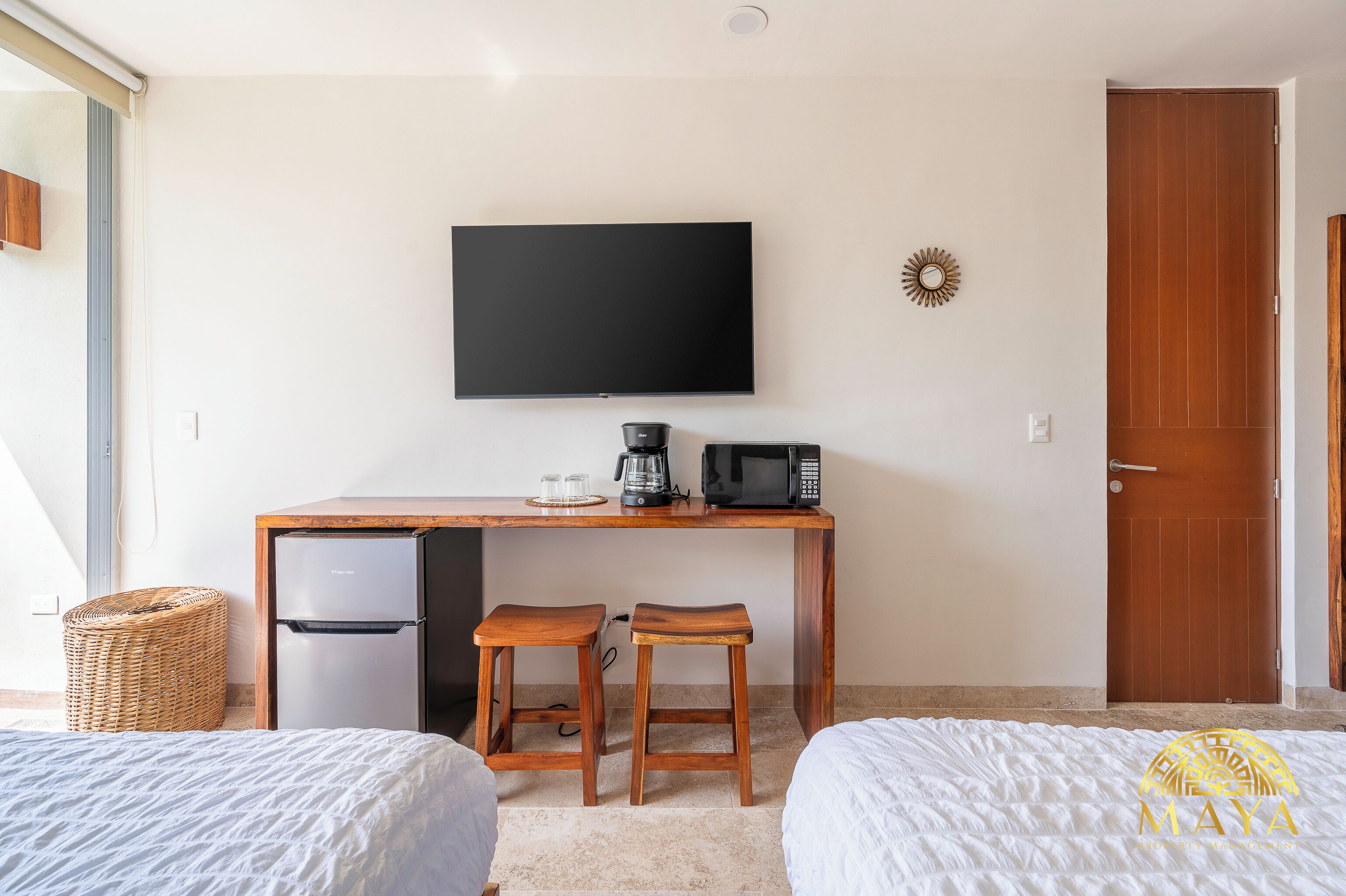 A hotel room with a bed, a desk with a TV, a coffee maker, and a microwave.