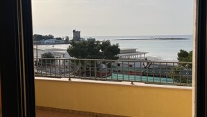 En balkon med udsigt til havet og et fjernt tårn.