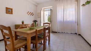 Un coin repas avec une table et des chaises en bois, une plante en pot et une fenêtre avec des rideaux.