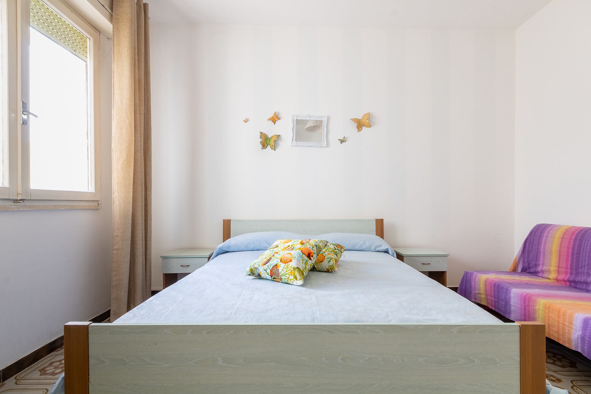 A bedroom with a bed, a nightstand, a chair, and butterfly wall decorations.