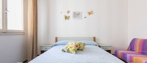 A bedroom with a bed, a nightstand, a chair, and butterfly wall decorations.