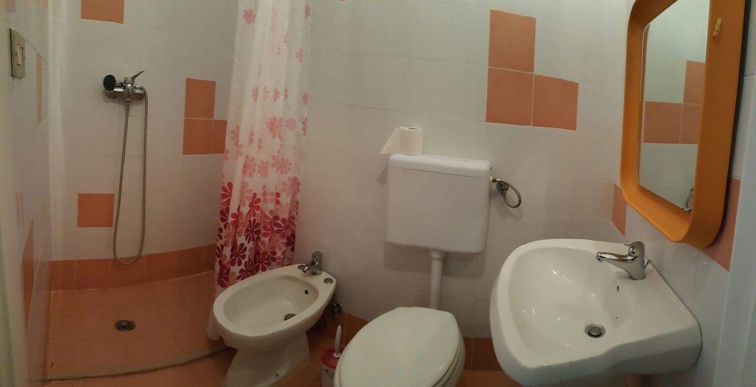A bathroom with a bidet, toilet, sink, and shower.
