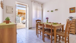 Un espace repas comprenant une table et des chaises, une plante en pot et une vue sur l’extérieur.