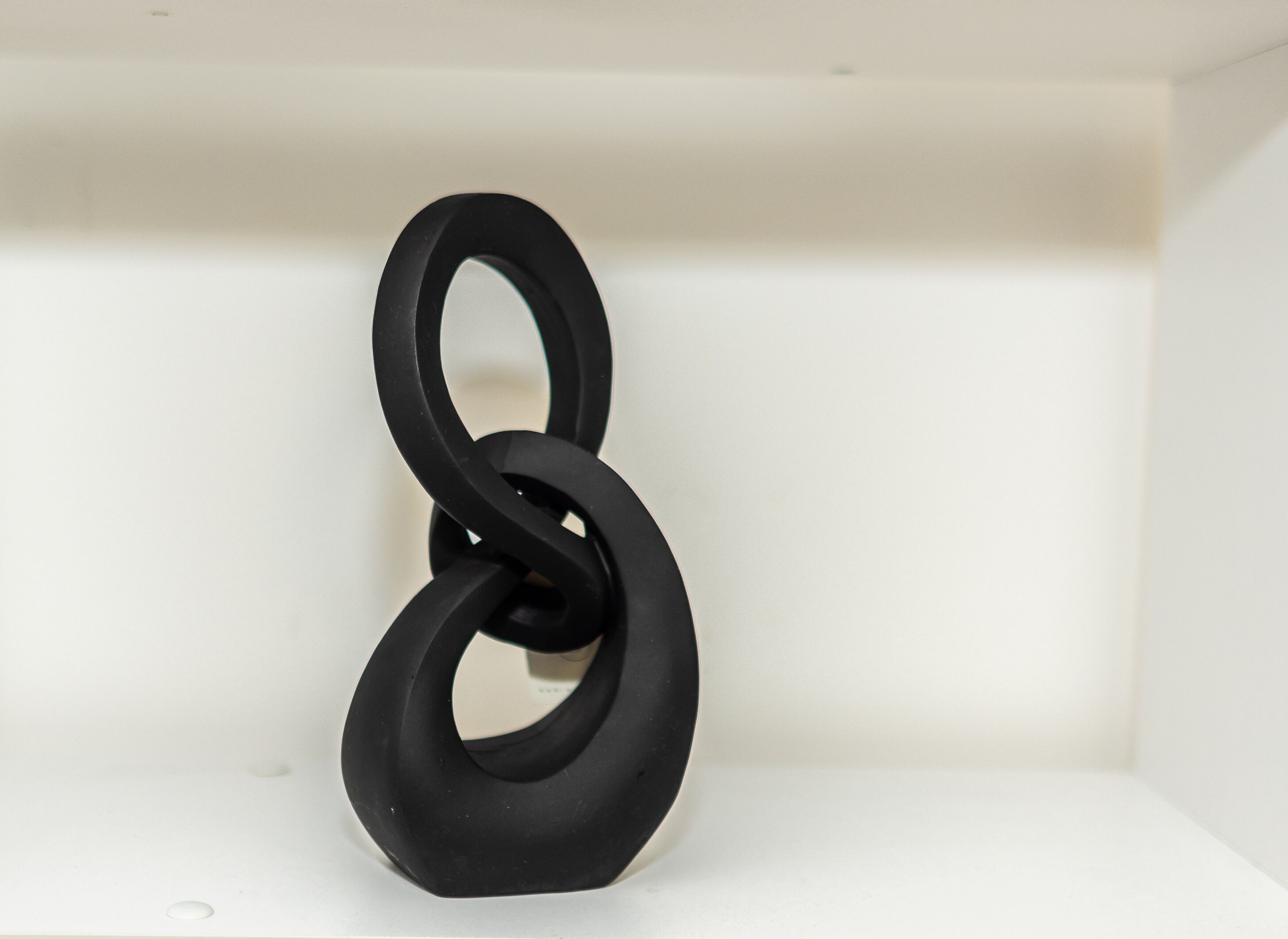 A black, abstract sculpture in a white room.