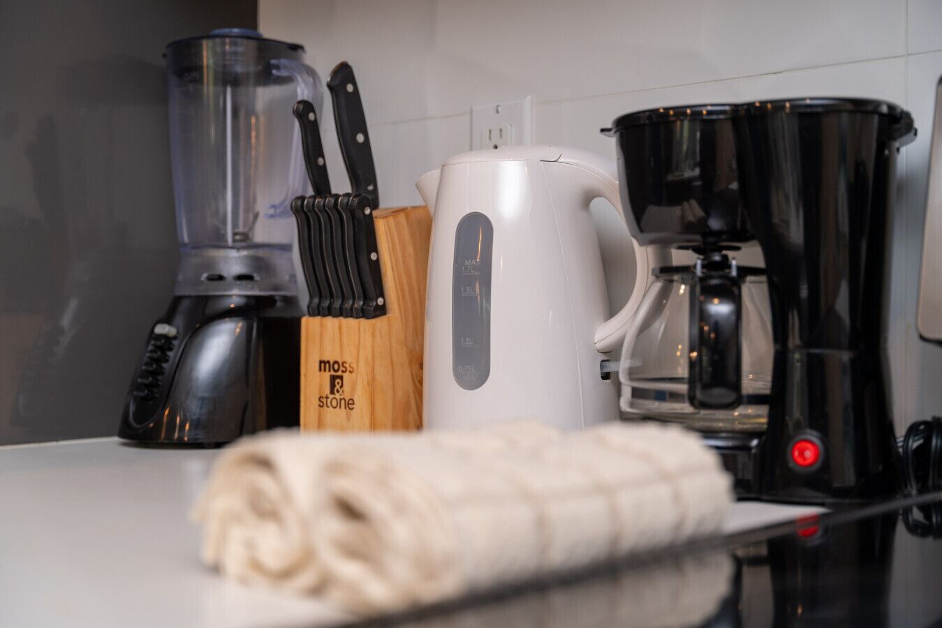 Eine Küchenarbeitsplatte mit Kaffeemaschine, Wasserkocher, Mixer und einem Messerblock.