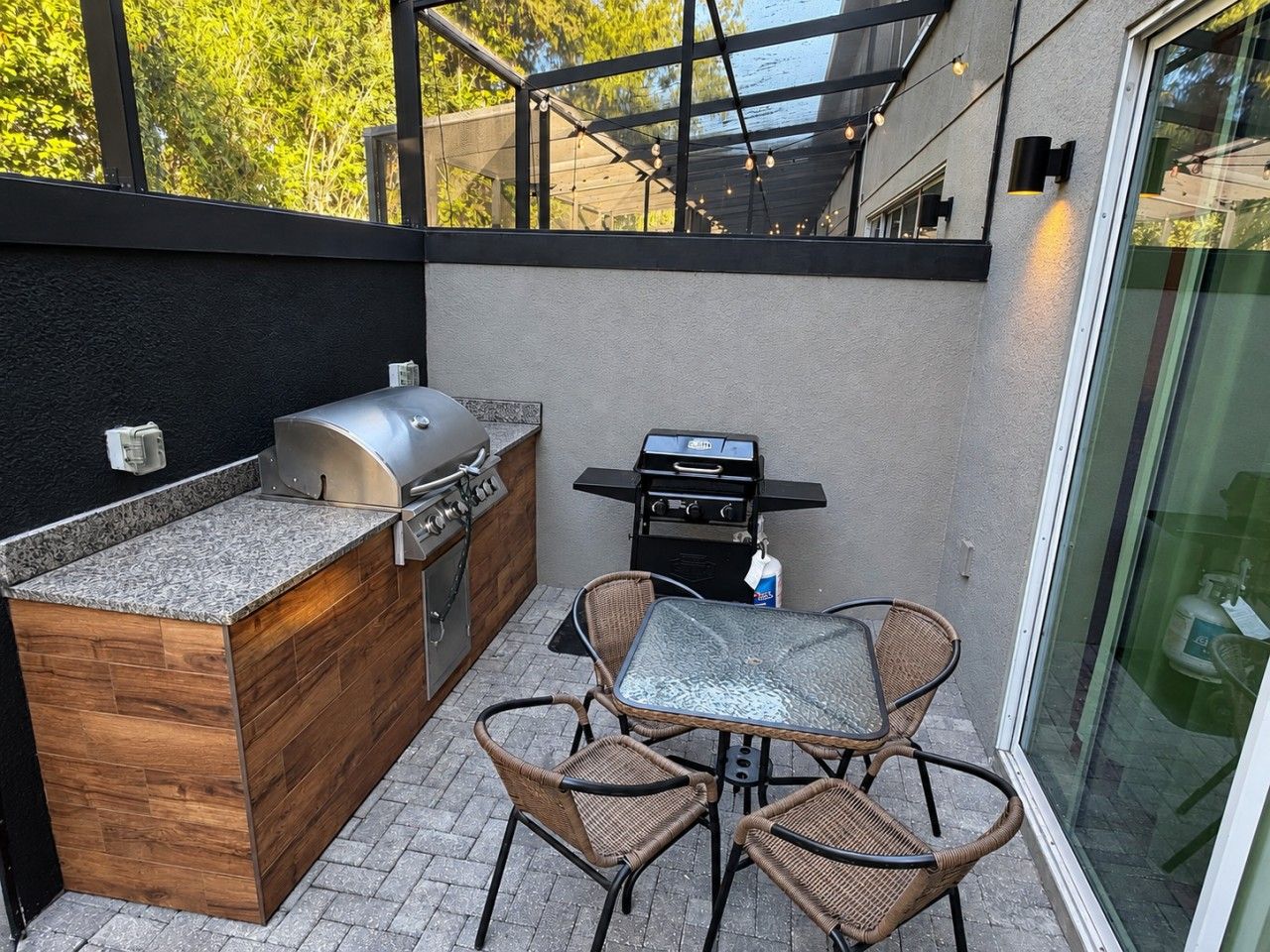 Un área de cocina al aire libre con una parrilla, horno integrado y una mesa de comedor con sillas.