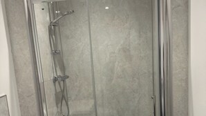 A modern bathroom with a glass-enclosed shower, a white sink, and a towel rack.