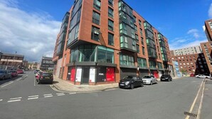 A multi-story building with a modern architectural design, featuring large windows and a prominent corner entrance.