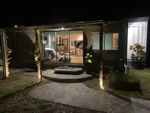 Una casa moderna con puerta de cristal, un camino de piedra y una pequeña zona de estar al aire libre.