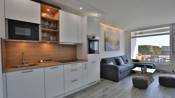 A modern kitchen with white cabinetry, a wooden countertop, and a built-in microwave. - Strandkoje 105 - Modern vacation apartment in Scharbeutz - Close to the beach, quiet & sunny (Scharbeutz)