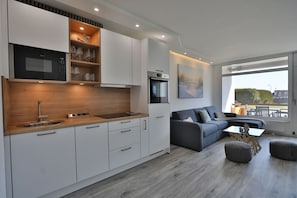 Een moderne keuken met witte kastjes, een houten aanrechtblad en een ingebouwde magnetron.