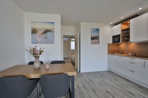 Een moderne keuken met witte kastjes, een houten aanrecht en een ingebouwde magnetron.