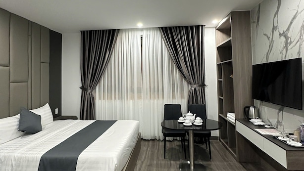 Une chambre d’hôtel moderne équipée d’un lit, d’un bureau, d’une chaise, d’une télévision et d’une machine à café.