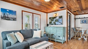 Una sala de estar acogedora con un sofá gris, un aparador de madera y un comedor con sillas de mimbre.