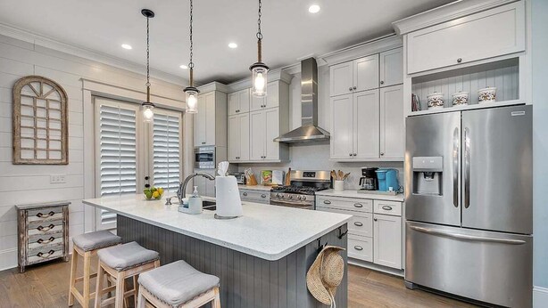 A kitchen with a central island, stainless steel appliances, and wooden bar stools. - 65 Water Oak Way-Ocean Oaks (Jekyll Island)