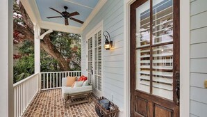 A covered porch with a ceiling fan, a wooden bench with cushions, and a wooden crate. - 65 Water Oak Way-Ocean Oaks (Jekyll Island)
