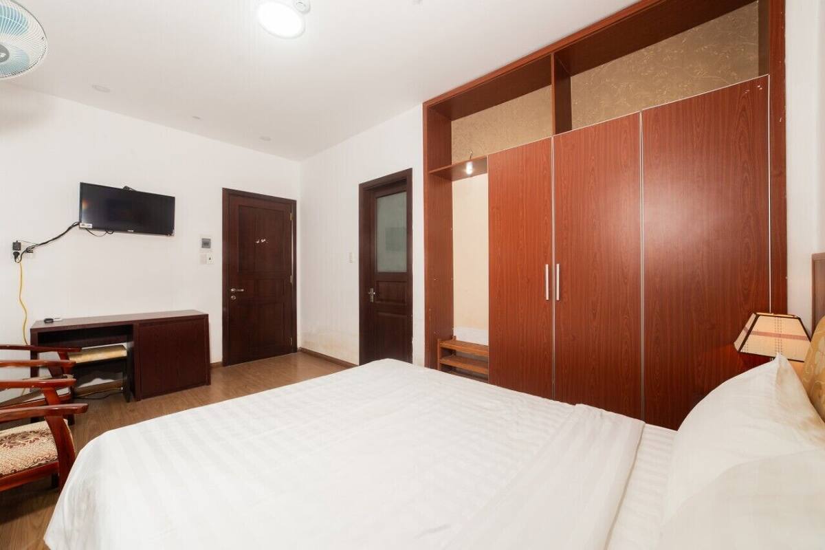 Een slaapkamer met een bed, een bureau, een televisie en een kledingkast.