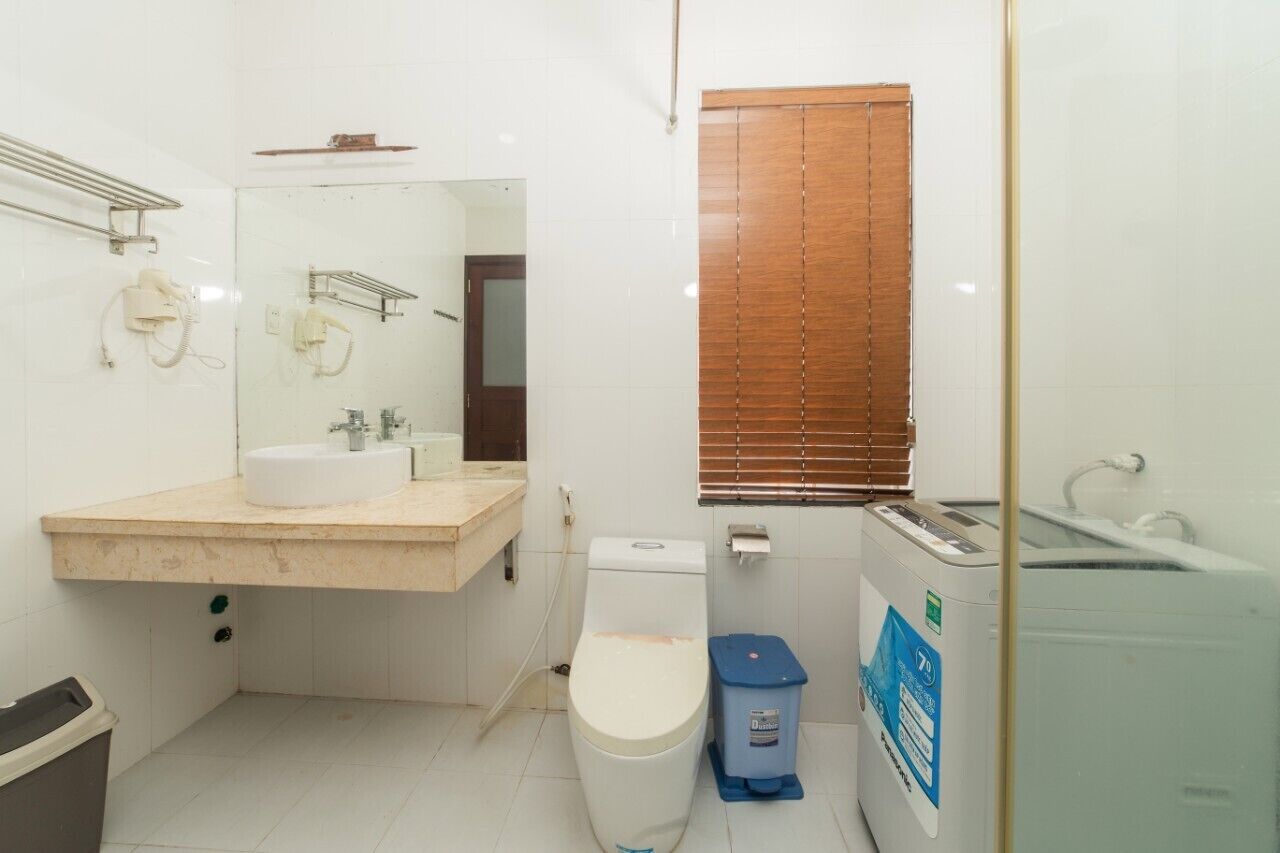 A small, compact bathroom with a white sink, toilet, and a washing machine.